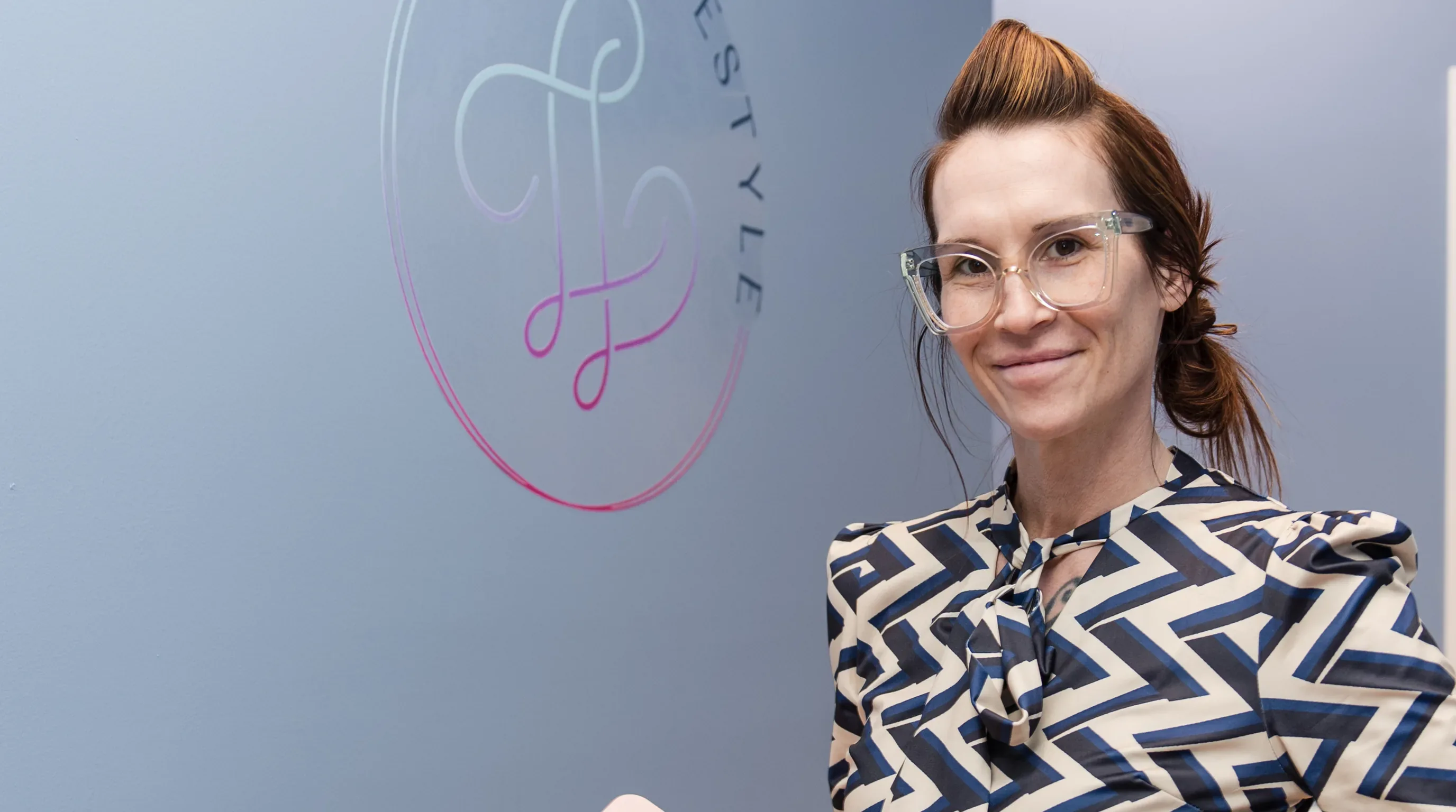 Dr. Sarah Secor-Jones beside the Lesh Lifestyle logo wall