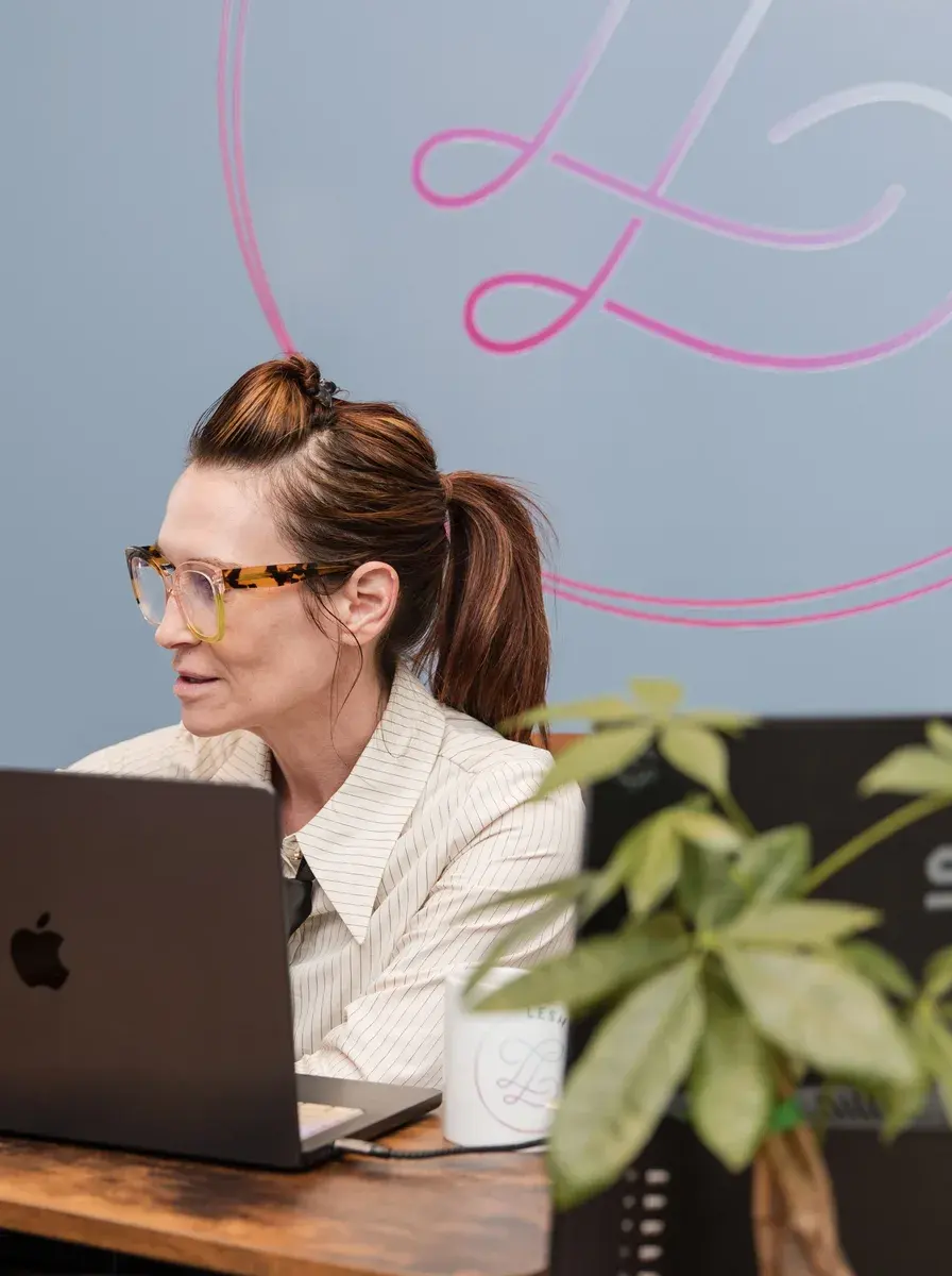 Dr. Sarah Secor-Jones working at her desk beneath the Lesh Lifestyle mural